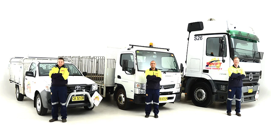 Swift Transport drivers standing beside a ute, taxi truck and prime mover